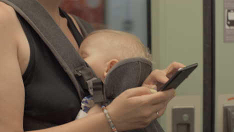 woman with baby using mobile when traveling by underground train