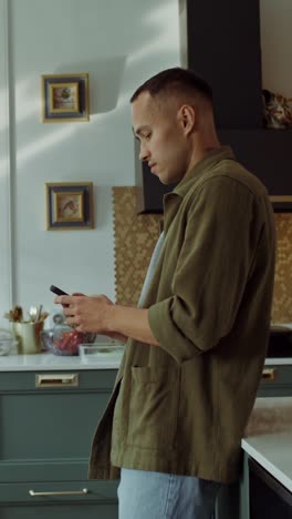 young man using phone in kitchen