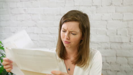 A-frustrated-and-stressed-young-woman-student-looking-at-bills-and-paperwork-in-an-office