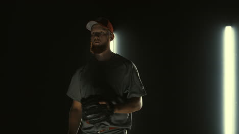 jugador de béisbol profesional caucásico lanzando una pelota hacia la cámara contra un fondo oscuro. 4k uhd