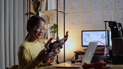 teen asian girl walking to look at the pictures on the wall while working about a cyborg hand at home