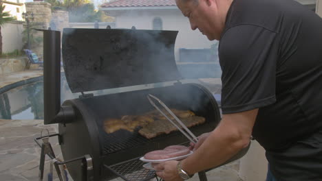 man opens bbq pit and puts sausage on to grill