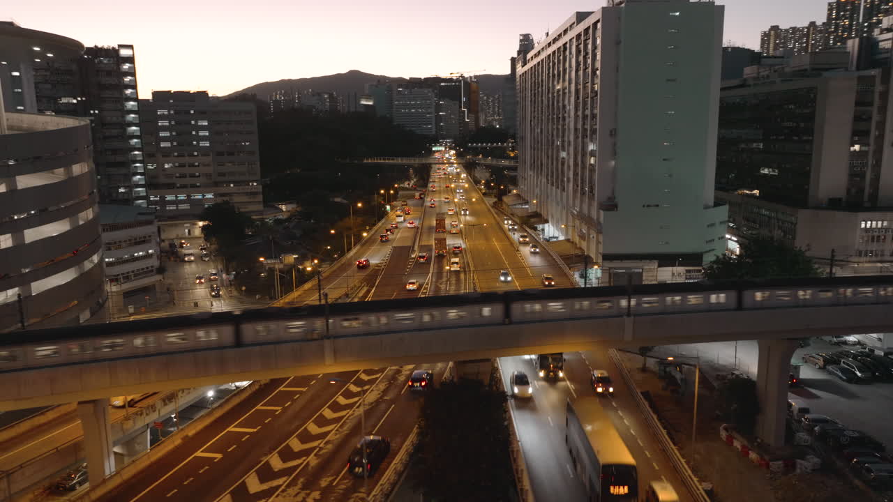 홍콩의 맑은 저녁에 붐비는 고속도로를 통해 고가도로를 달리는 기차