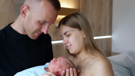 caucasian couple talking and smiling holding their newborn. happy family portrait close up.