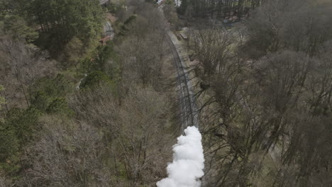 Slow-motion-aerial-drone-shot-following-a-steam-train-engine-moving-down-the-tracks-in-Chattanooga,-TN