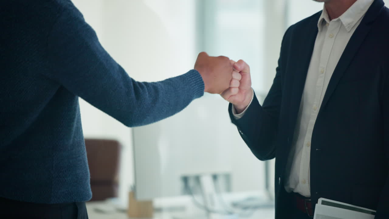 Due uomini d'affari che si danno il pugno in un ufficio