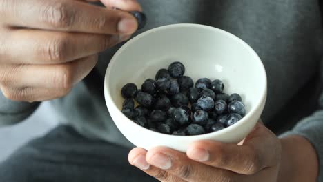 person eating blueberries from a bowl