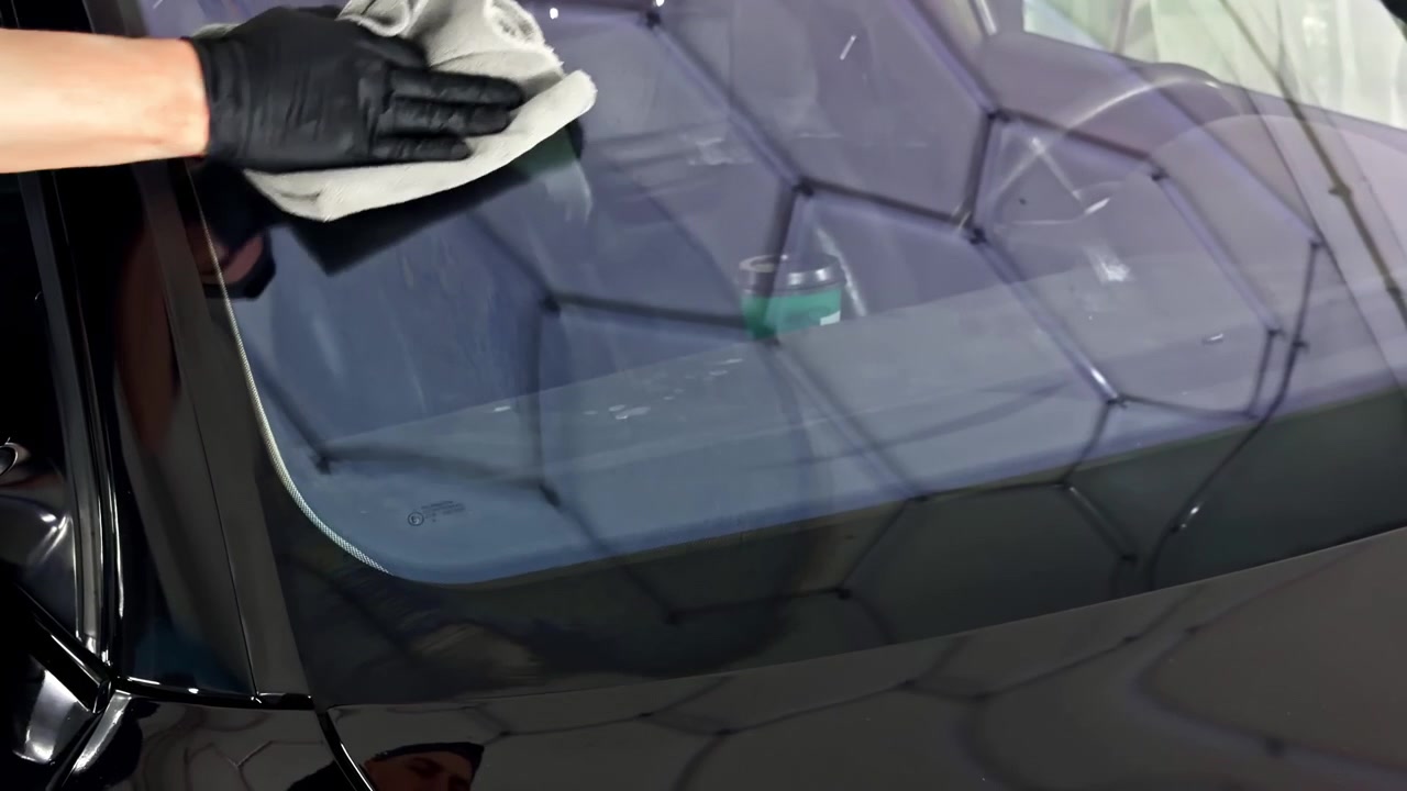 Professionele detailer brengt keramische coating aan op een autoruit in een schone garage