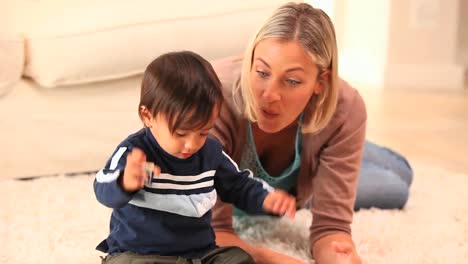 bebé jugando con su madre en la alfombra