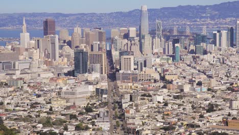 top aerial view of the skyline of downtown san francisco, california - a man hikes down the twin peaks mountain