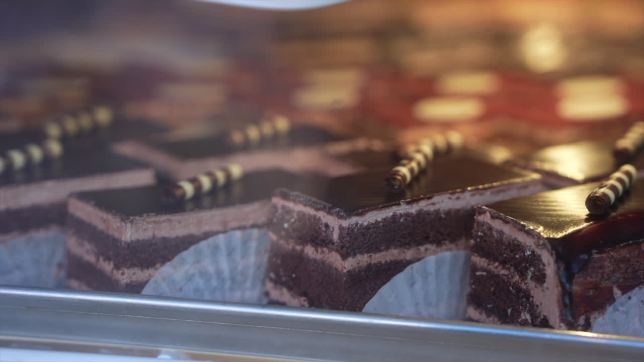 Delight in the close-up view of rich chocolate pastries with creamy layers, captured in soft lighting. This detailed shot highlights gourmet dessert presentation in a patisserie setting