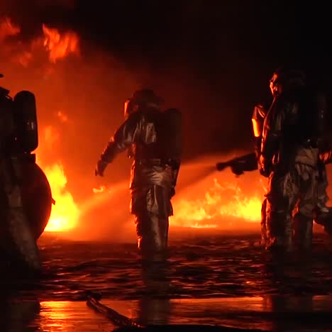 bomberos con trajes resistentes al calor o materiales peligrosos luchan contra un incendio intenso por la noche 2