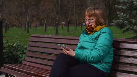 mujer mayor usando un teléfono inteligente en un parque