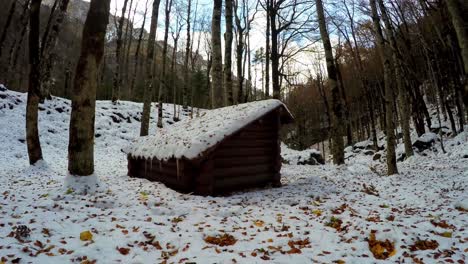 old log cabin with icicles located in winter forest surrounded by mountains