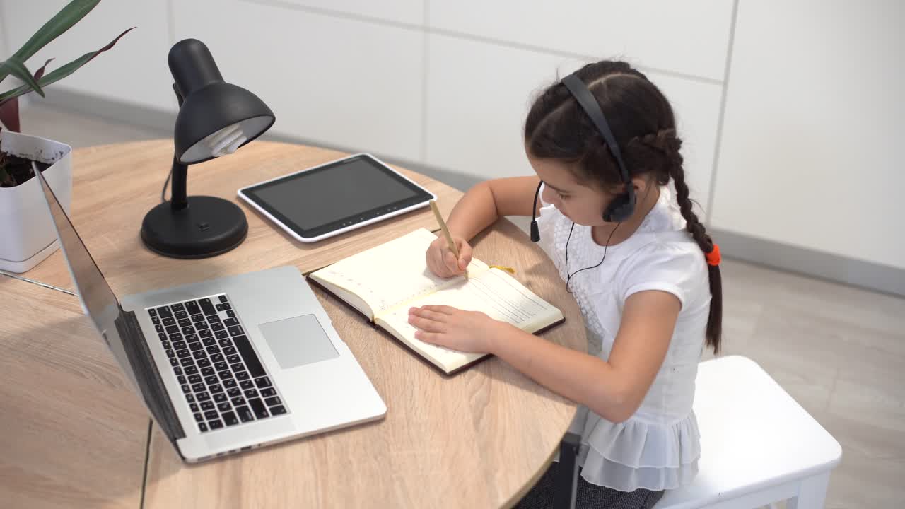 niña pequeña estudiante estudiando en línea con computadora portátil en casa, nueva normalidad. covid-19 coronavirus. distanciamiento social, educación en el hogar.