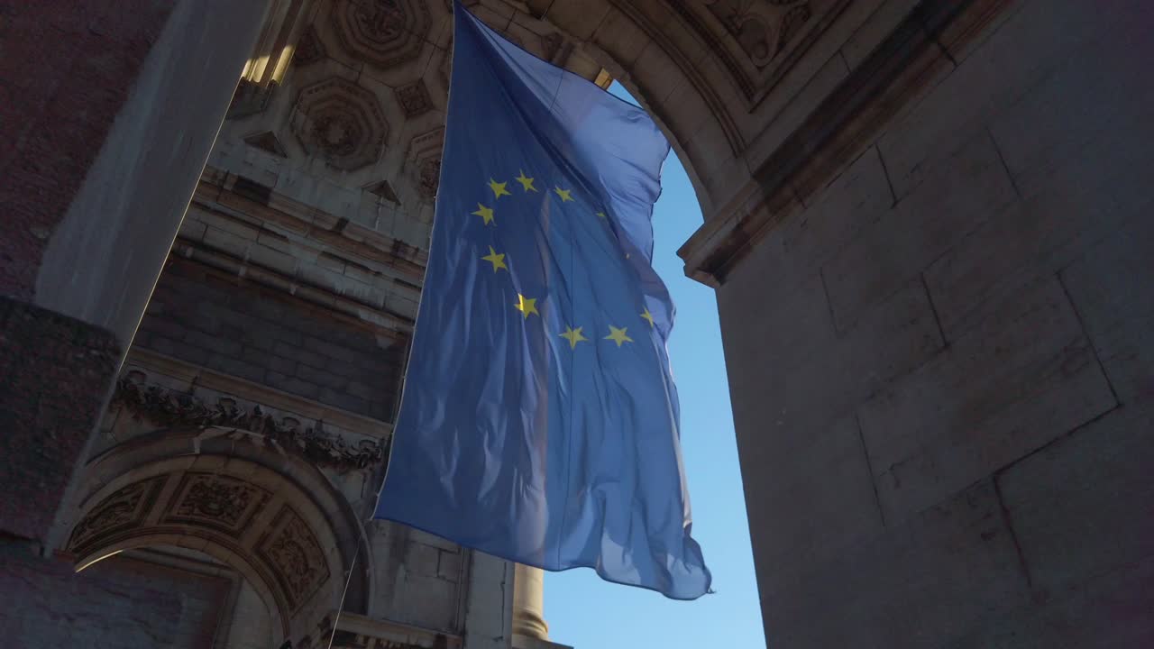 Bandiera dell'UE che sventola tra i pilastri in pietra dell'Arco del Cinquantenario.