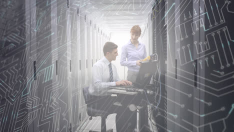 man and woman working in computer server room while a glowing circuit board moves in foreground