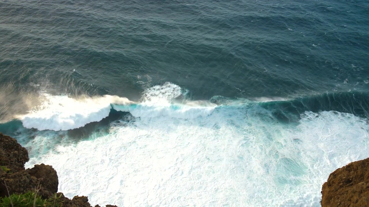 Powerful ocean waves crashing against rocky cliffs, with white foam and deep blue waters in madeira