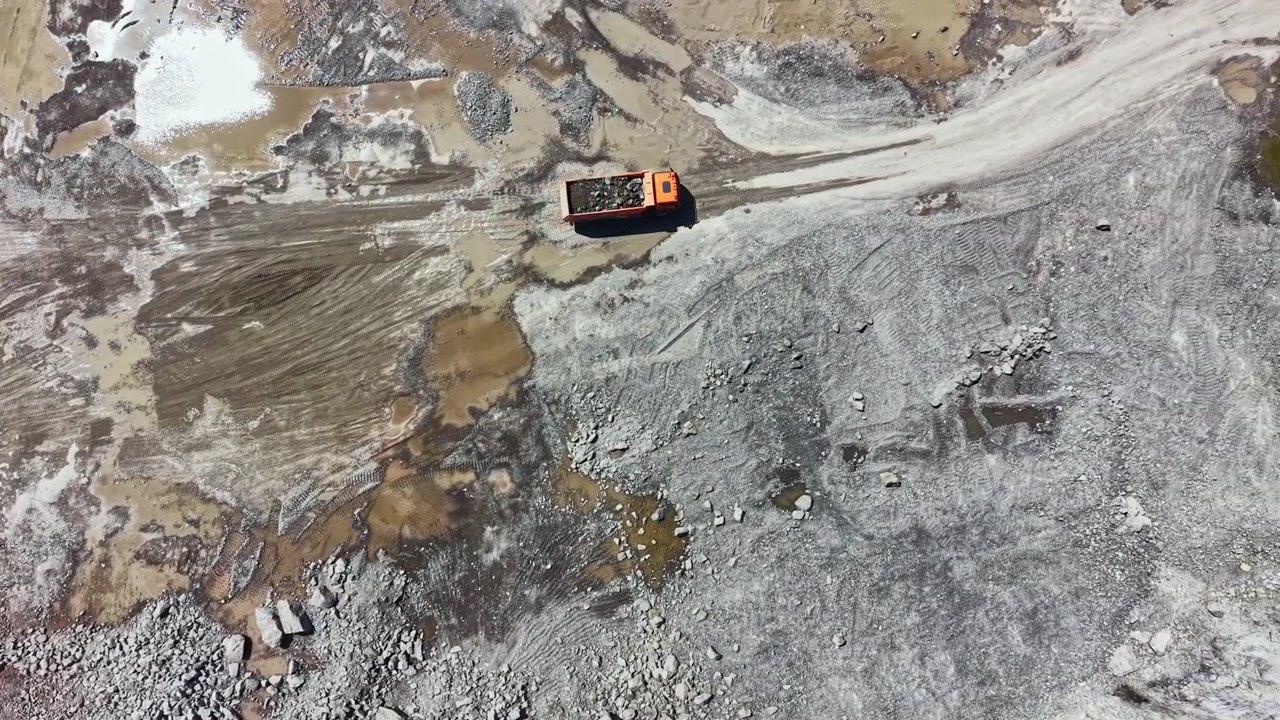 Granite quarry operation shows truck transporting raw materials across the rough terrain during daytime