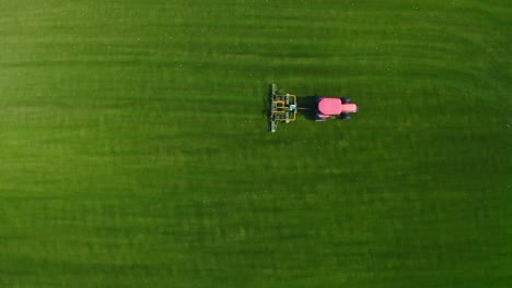 Red-Tractor-Cut-Grass-on-Green-Field---Aerial-Top-Shot-View