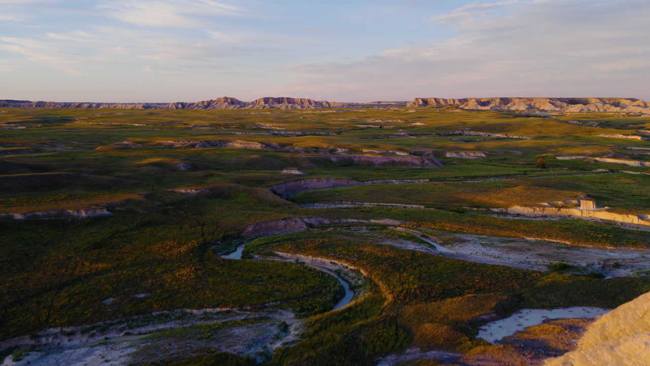 Drone Views of Jagged Badlands at Dusk With Glowing Sky Backdrop