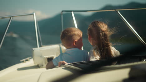 little children look out of motorboat hatch travelling across ocean on sunny day. happy siblings enjoy cruise by fast yacht in sea bay on vacation