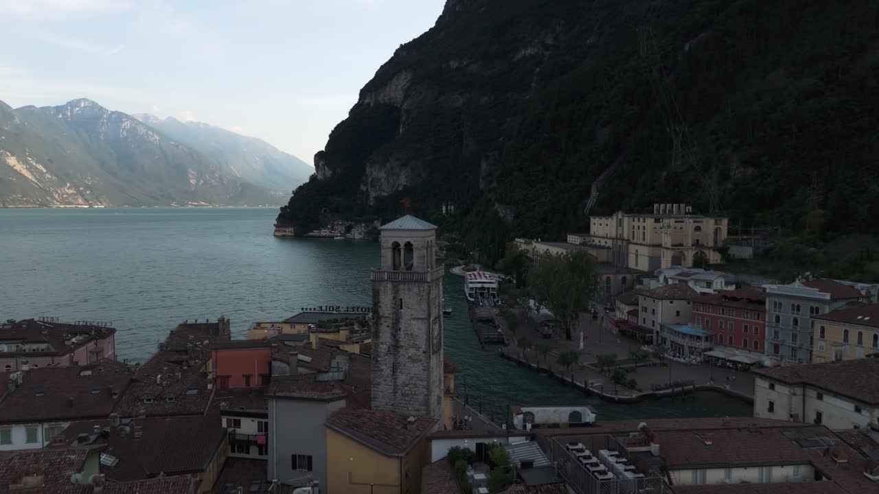 Riprese con drone di una pittoresca cittadina italiana vicino al Lago di Garda, con cime montuose e acque del lago sullo sfondo, che unisce fascino storico e paesaggi naturali mozzafiato.
