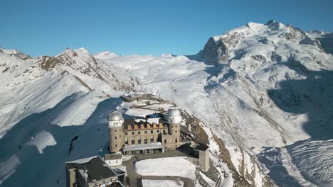 aerial pullback reveals famous gornergrat observation platform on clear winter day