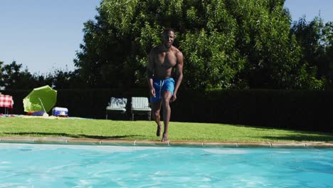 mixed race man having fun jumping into a swimming pool