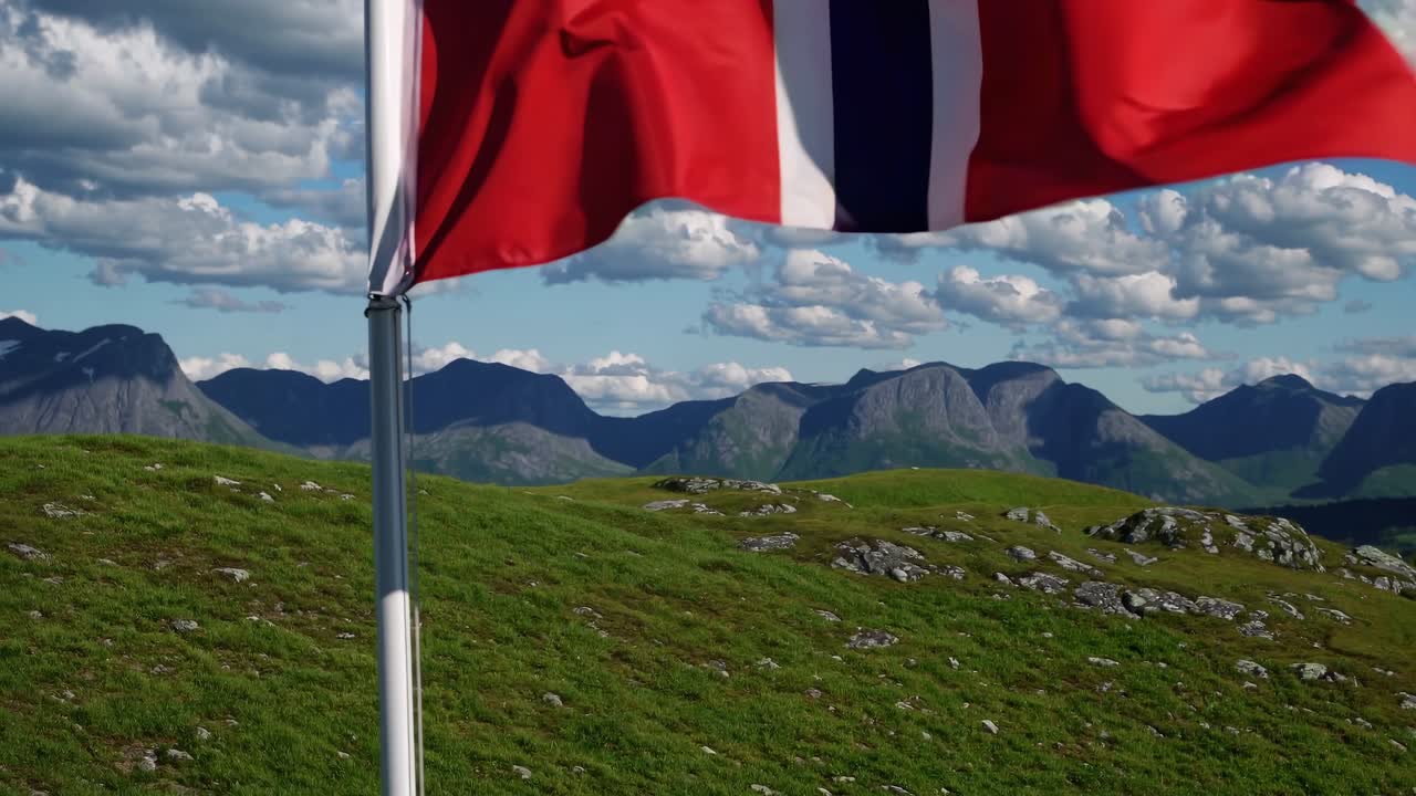 Norsk flagg som vaier i vinden med et vakkert fjellandskap.