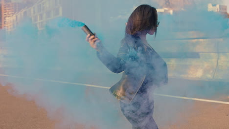 woman-dancing-with-blue-smoke-bomb-in-city-young-rebellious-girl-celebrating-creative-expression-with-dance-in-street-slow-motion