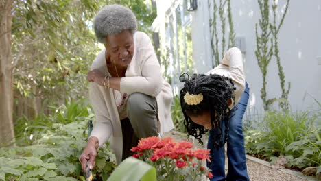 happy african american grandmother, granddaughter and grandson gardening together, slow motion