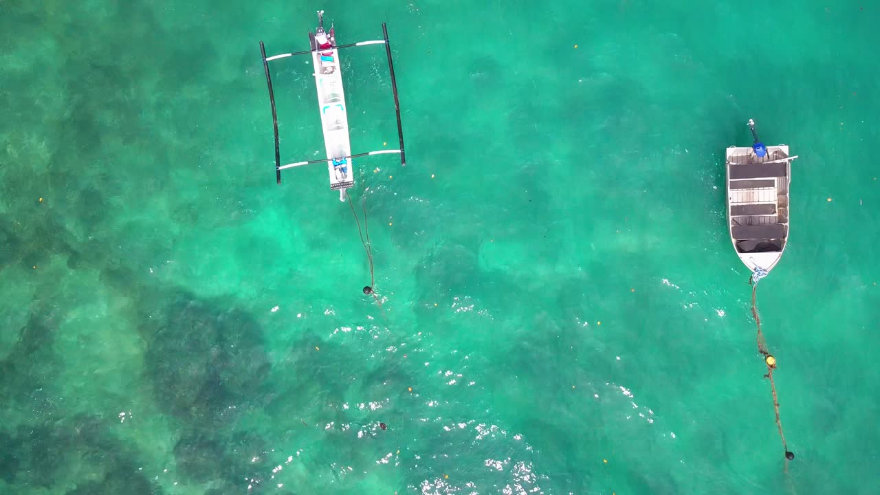 Drone video of a blue sea in Bali with 2 boats floating Uluwatu Indonesia