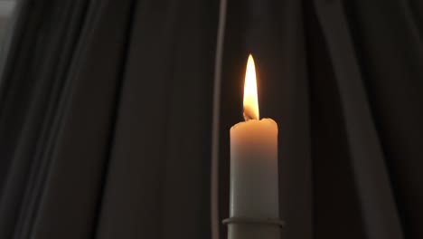 handheld shot of swaying candle on dark curtain background