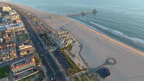 beautiful coastal 4k aerial view of the california from the sky as the shot flies over traffic towards a pier at sunset.