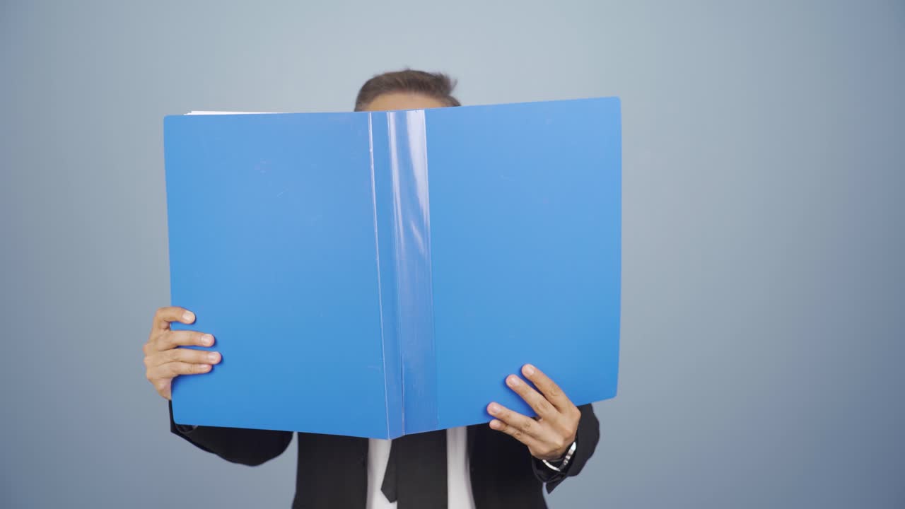 Businessman looking from behind files.