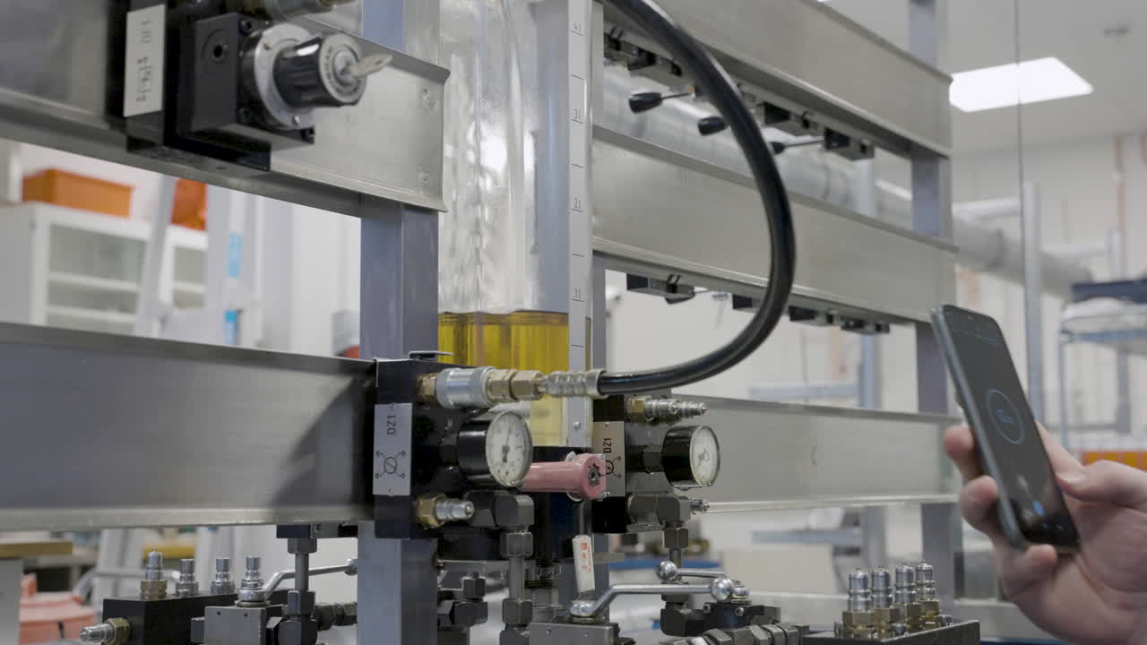 mano del profesor registrando el tiempo que lleva llenar un tanque de aceite del sistema hidráulico usando un teléfono móvil