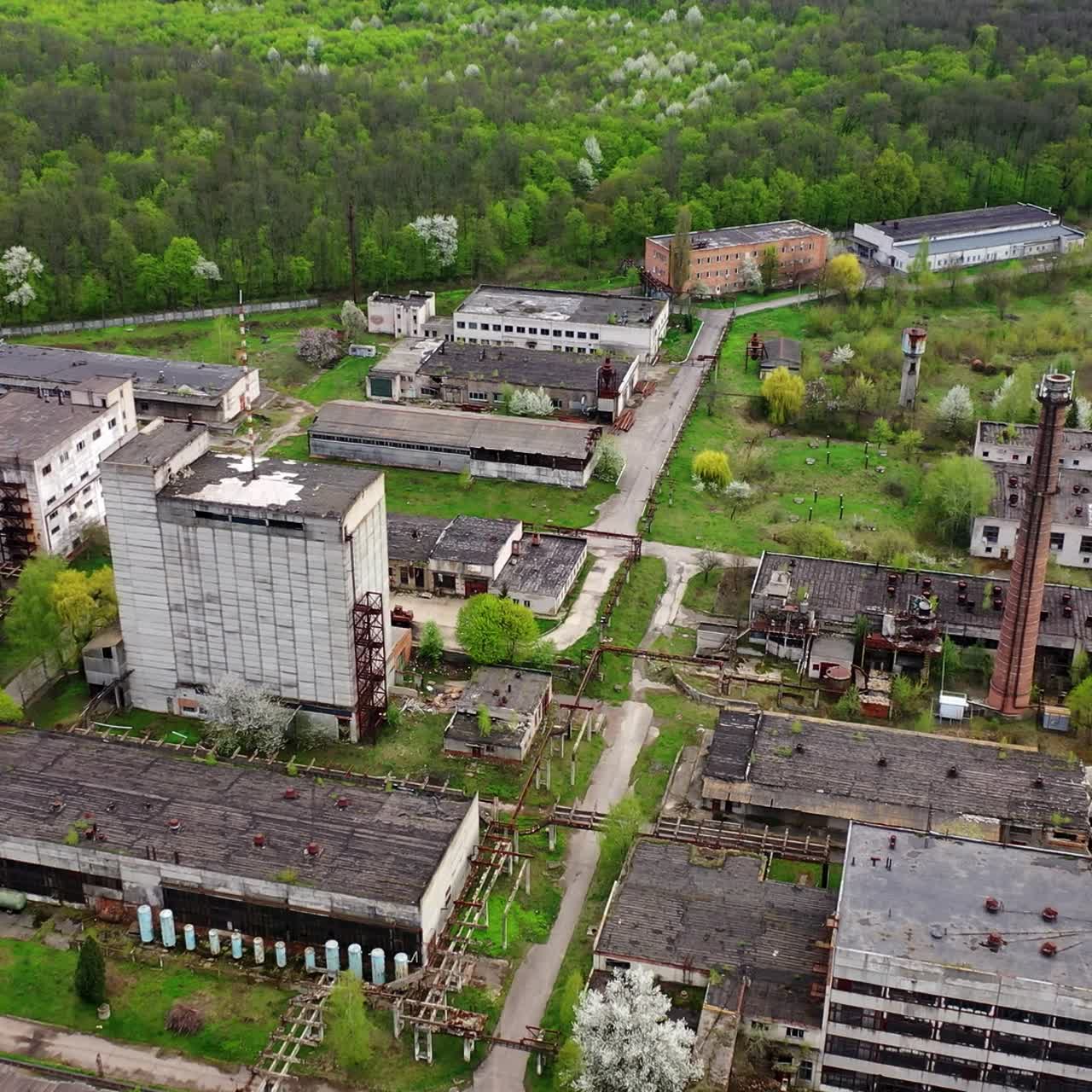 Abandoned factory industrial zone. Old factory warehouses. Ruined buildings on green nature background. Aerial drone view