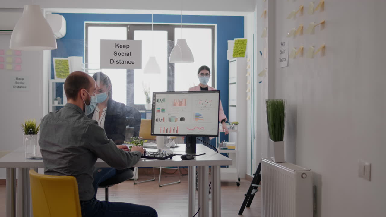 Teammedarbejdere med beskyttende mundbind, der arbejder på et marketingprojekt.
