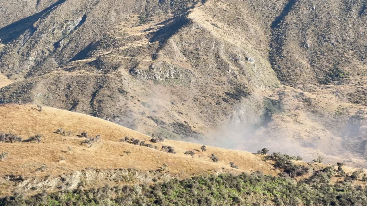 Low mist drifts across dry mountain slopes, natural daylight, wide static shot, tranquil atmosphere