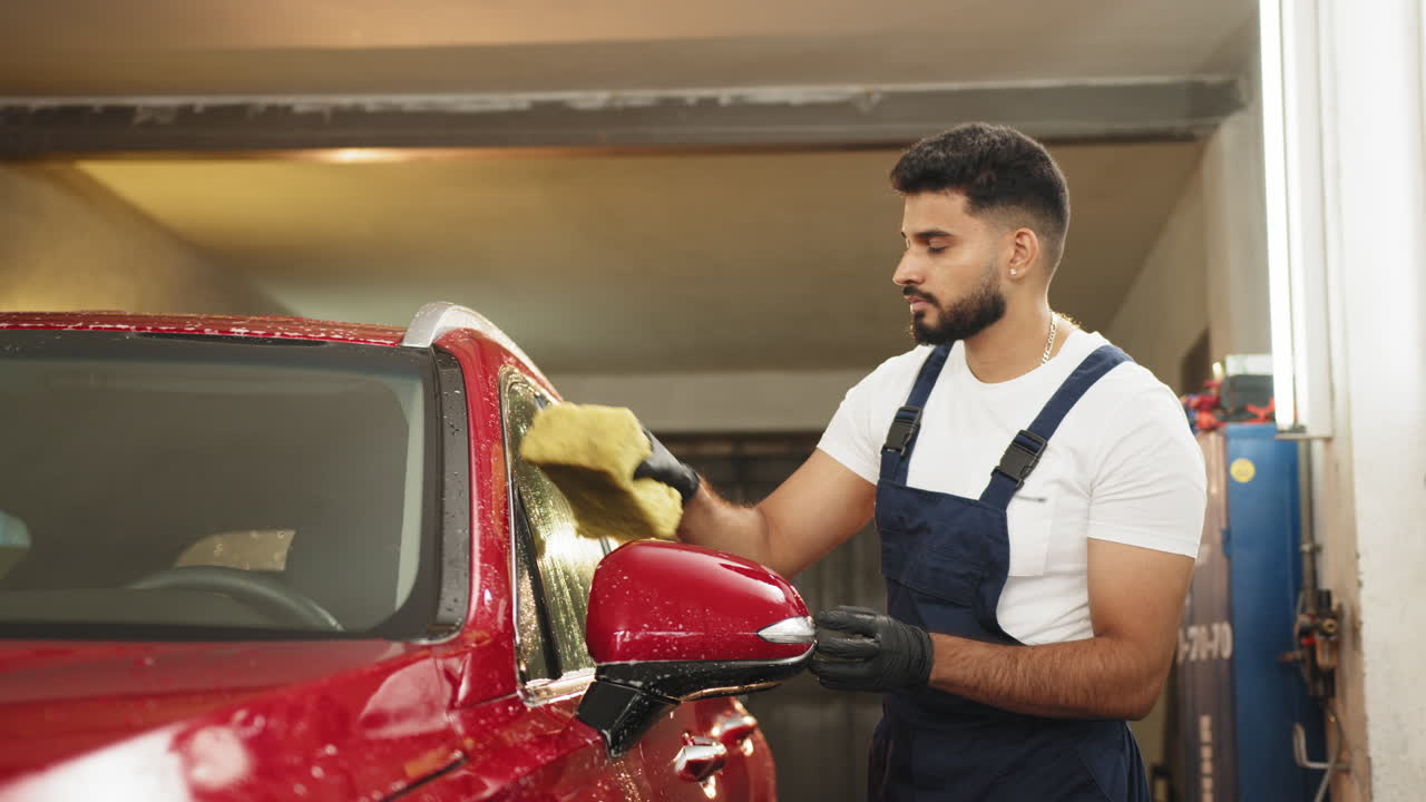 hombre lavando un coche rojo en un garaje