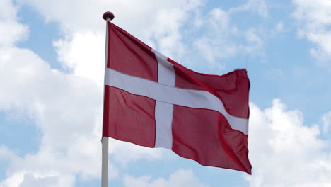 danish flag fluttering in windy day against sky with clouds