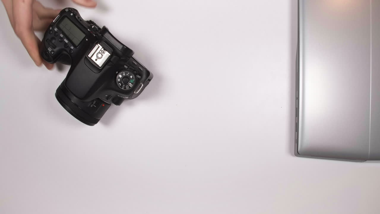 Posizionamento di laptop, fotocamera DSLR e disco esterno sul tavolo - ripresa dall'alto