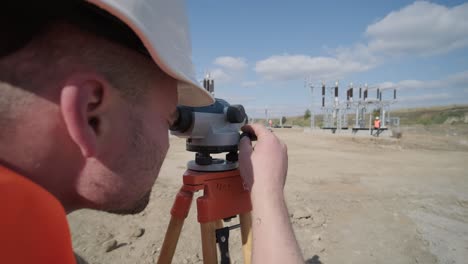 un ingeniero topógrafo toma mediciones en la construcción de una subestación de transformador