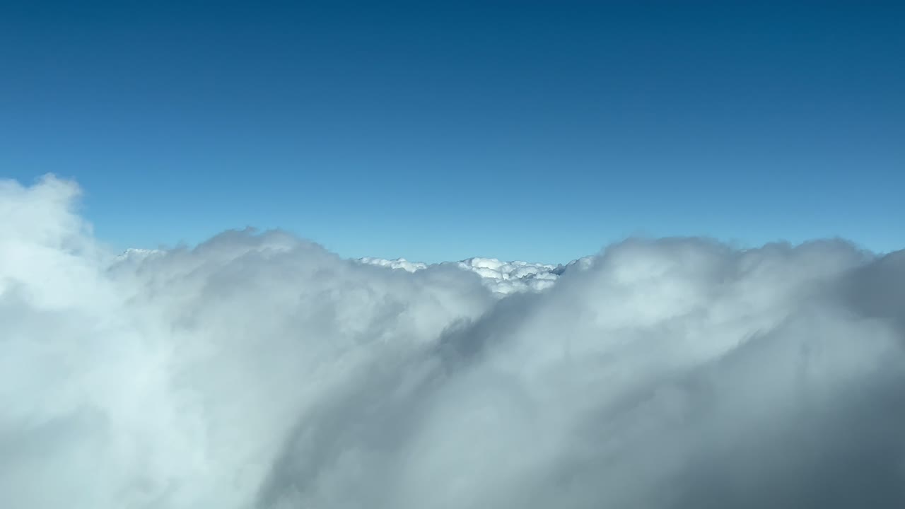 하늘을 가로질러 실제 시간 비행 중에 제트 객실에서 촬영 된 구름 장면. 화려한 밝은 파란 하늘과 함께 진정시키는 겨울 어리들이 많습니다.