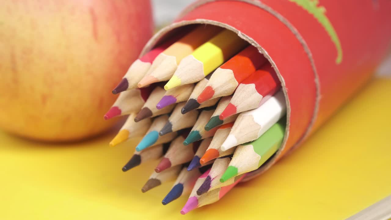 lápices de colores en un recipiente con una manzana
