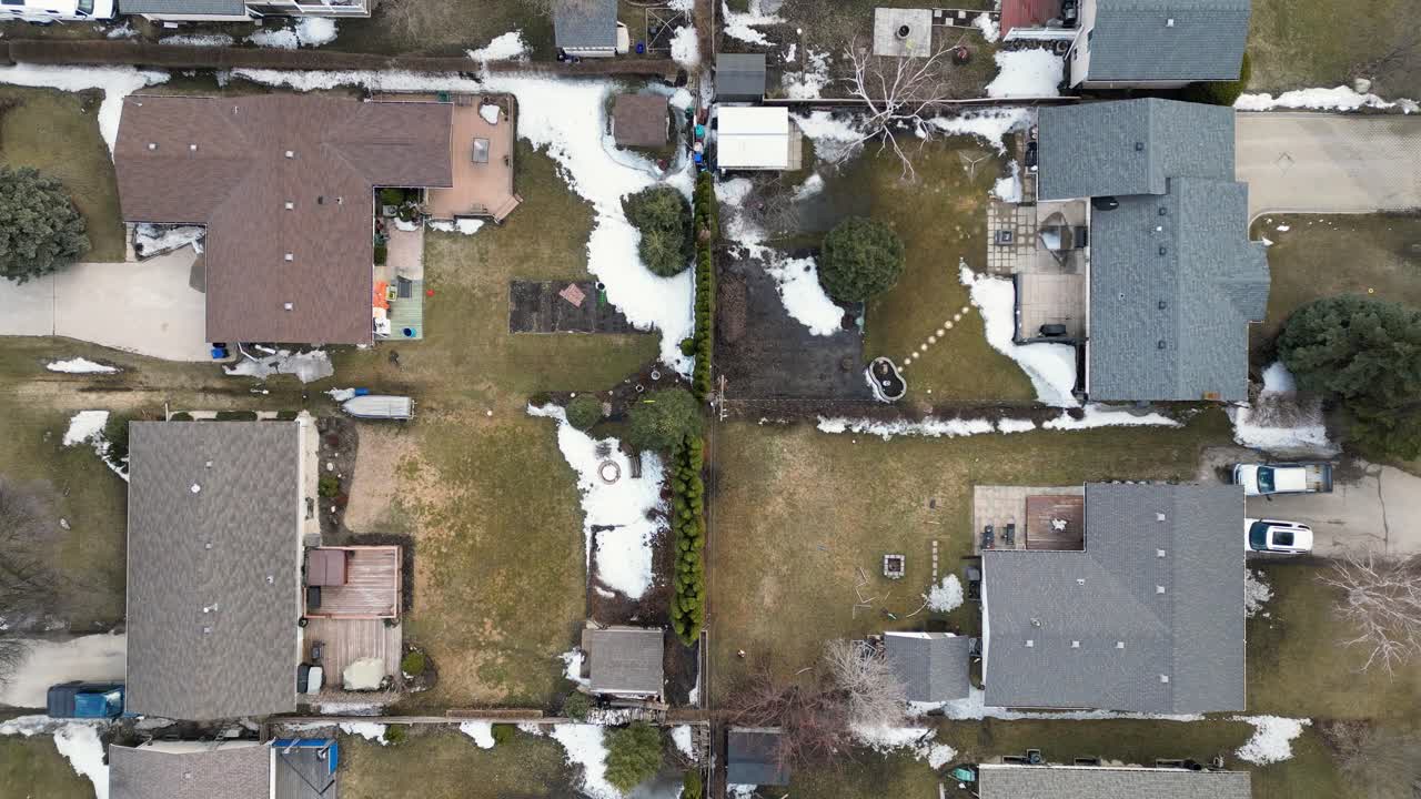 Top down drone shot of four neighboring homes with backyards gardens and sheds as the camera rises