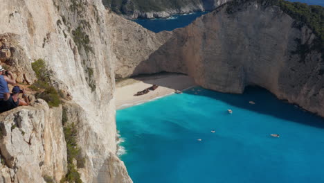 tourists at shipwreck viewpoint, offering best view of navagio beach with remains of mv panagiotis in greece