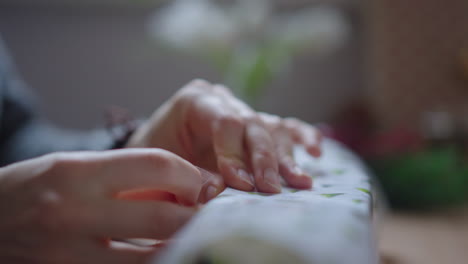 extreme close up of host, packing a gift box, with decorative white gift wrap