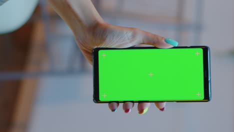 vertical video: housewife holding smartphone with green screen